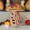 This shows a handmade mushroom decoration. Made from a gourd, it has a fern carved in the stock and wood burned bee artwork on top. 